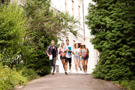 Group of attractive teenage students running from university.の写真素材