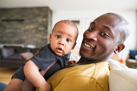 Young afro-american father holding his baby son in the armsの写真素材