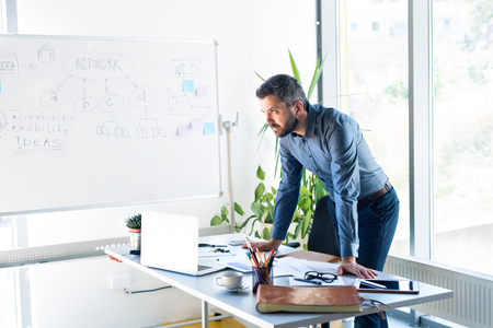 Thoughtful businessman with laptop in his office.の写真素材