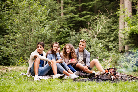 Teenagers camping in nature, sitting at bonfire.の写真素材