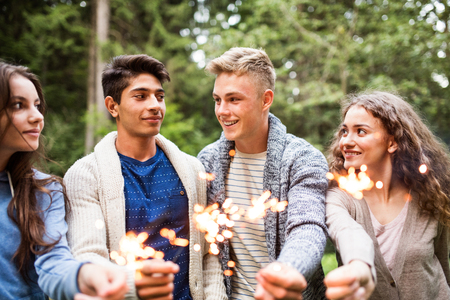 Beautiful teenagers in forest with sparklers.の写真素材
