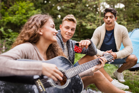Teenagers in front of tent camping in forest.