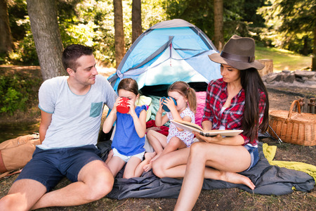 Beautiful young family with daughters camping in forest.の写真素材