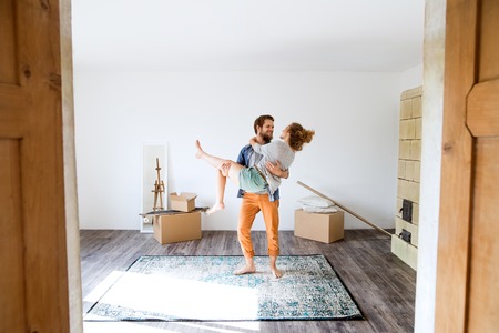 Man carrying woman in his arms, moving in new house.