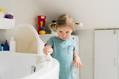Little girl in bathroom cleaning bathtub with a brush.の写真素材