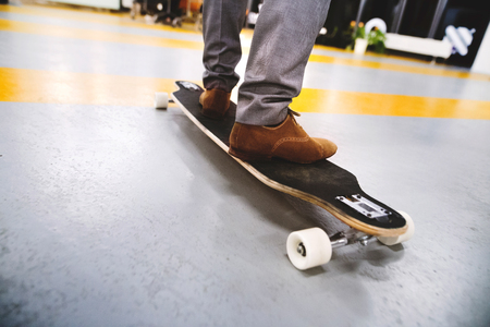 Unrecognizable businessman standing on longboard.の写真素材