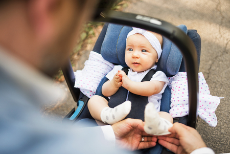 Father with baby daughter sitting in car safety seat.の写真素材