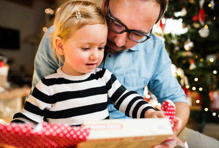 Little girl with her father opening Christmas present.の写真素材