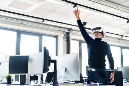 Mature businessman with VD goggles in the office.