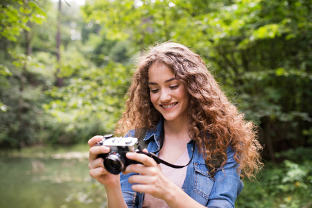 Teenage girl hiking in forest, taking pictures with camera.の写真素材