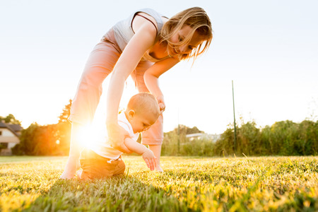 Baby boy with his mother outside in the garden.の写真素材