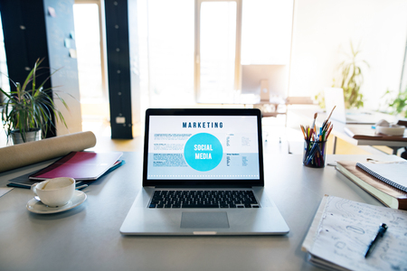 Office desk with laptop, coffee cup and office suppliesの写真素材