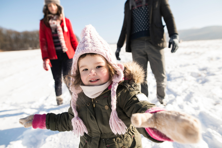 Father and mother with their daughter on a walk, winter nature.の写真素材