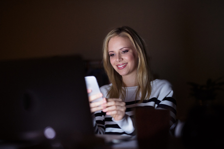 Woman with laptop and smartphone, texting.の写真素材