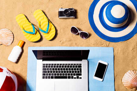 Summer vacation composition. Sandals, hat, laptop and smartphone