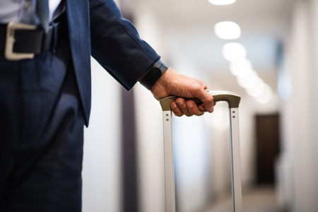 Unrecognizable businessman with luggage in a hotel corridor.の写真素材