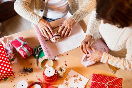 Unrecognizable senior couple in sweaters wrapping Christmas giftの写真素材