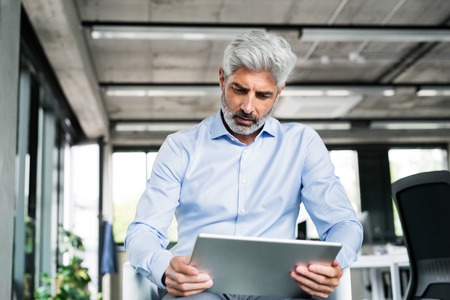 Mature businessman with tablet in the office.の写真素材