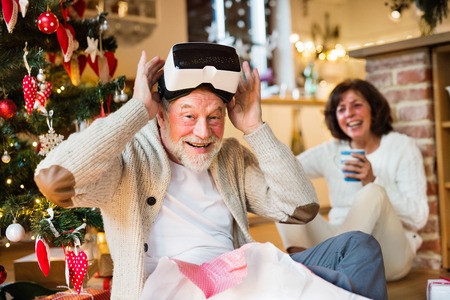 Senior couple in front of Christmas tree with VR goggles.