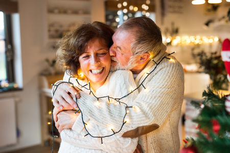 Senior couple hugging at home at Christmas time.の写真素材