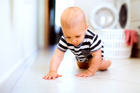 Baby boy by the washing mashine in the kitchen.の写真素材