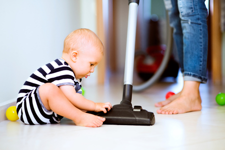 Young mother with a baby boy doing housework.の写真素材