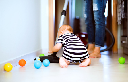 Young mother with a baby boy doing housework.の写真素材