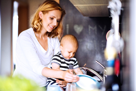 Young mother with a baby boy doing housework.の写真素材