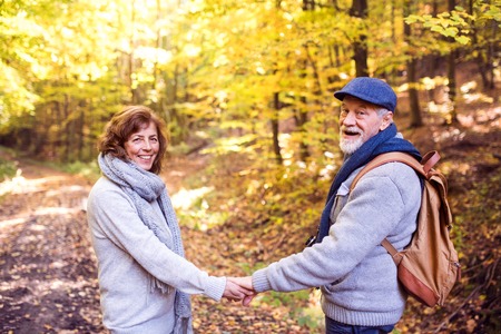 Senior couple on a walk in autumn forest.