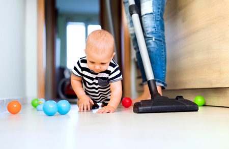 Young mother with a baby boy doing housework.の写真素材