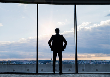 Mature businessman standing at the window in a hotel.の写真素材