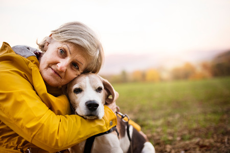 Senior woman with dog on a walk in an autumn nature.の写真素材