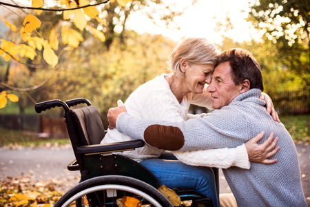 Senior couple in wheelchair in autumn nature.の写真素材