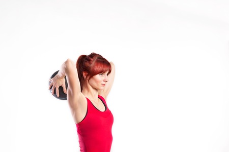 Fitness woman in red tank top holding medicine ball. Studio shotの写真素材