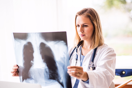Female doctor with x-ray , working at the office desk.