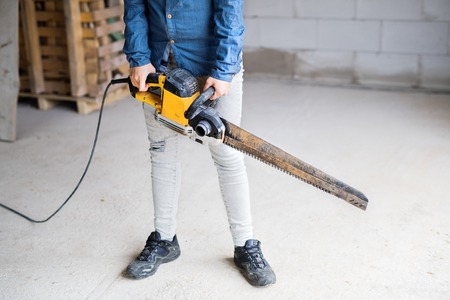 Young woman worker with saw on the construction site.の写真素材