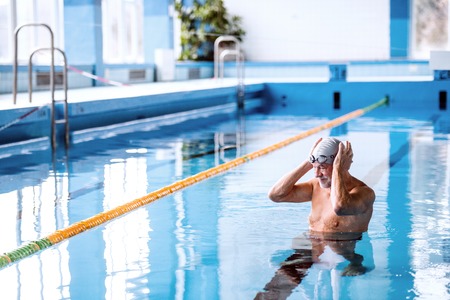 Senior man in an indoor swimming pool.の写真素材