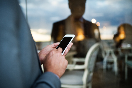 Businessman with smartphone in an outdoor hotel cafe.の写真素材