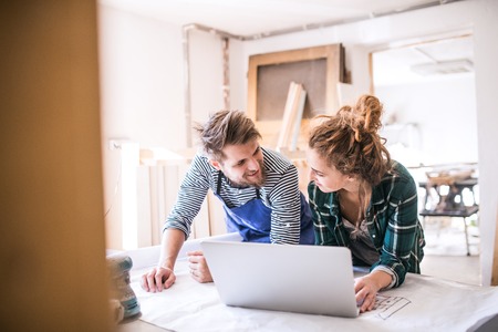 Young couple with laptop in the carpenter workroom.の写真素材