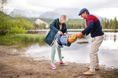 Senior couple with little boy at the lake.の写真素材