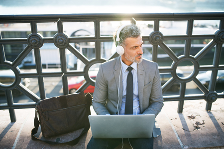 Mature businessman with a laptop in a city.の写真素材