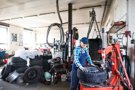 Senior female mechanic repairing a car in a garage.の写真素材
