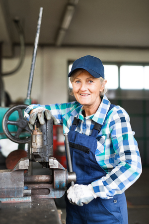 Senior female mechanic repairing a car in a garage.の写真素材
