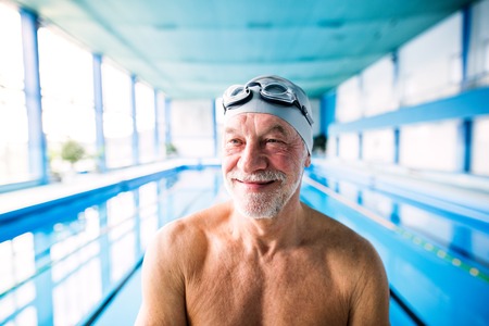 Senior man standing in an indoor swimming pool.の写真素材