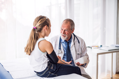Senior doctor checking a small girl in his office.の写真素材