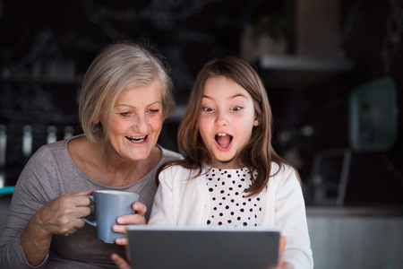 A small girl and grandmother with tablet at home.