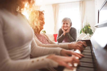 A girl with mother and grandmother playing the piano.の写真素材