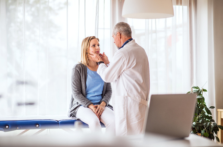 Senior doctor examining a young woman in office.の写真素材