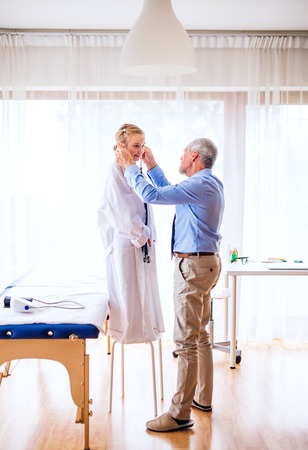 Senior doctor and a small girl with stethoscope in his office.の写真素材
