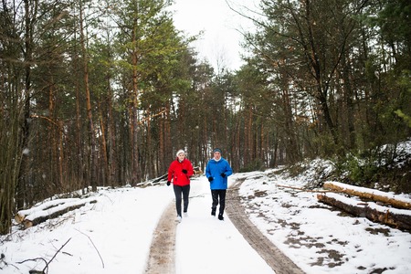 Senior couple jogging in winter nature.